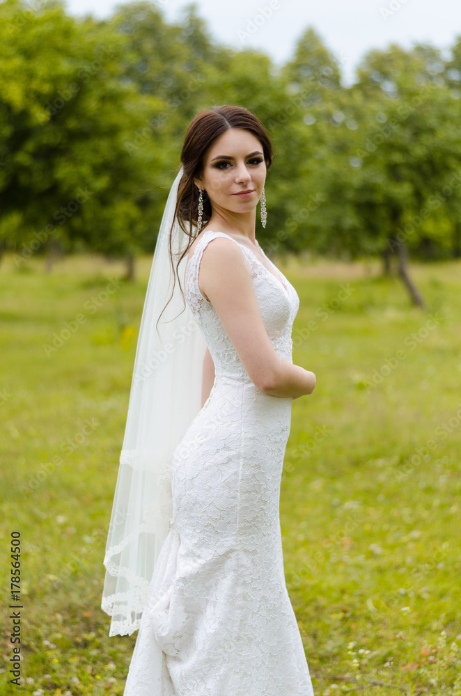 A beautiful married girl in wedding dress, posing for a photo shooting in an belarusian village. Green background