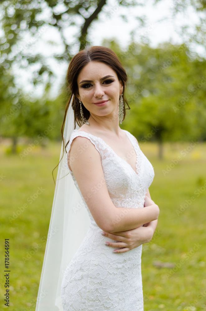 A beautiful married girl in wedding dress, posing for a photo shooting in an belarusian village. Green background A beautiful married girl in wedding dress, posing for a photo shooting in an belarusian village. Green background