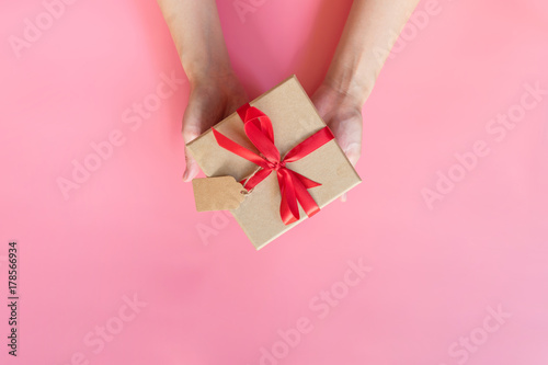 top view hand woman holding brown gift box for new year on pink pastel color background with space.