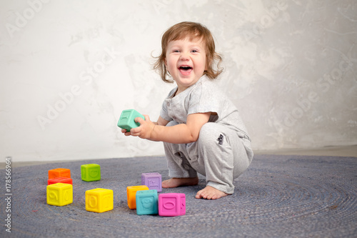 Little happy girl playing with toy on floor. Kindergarten.