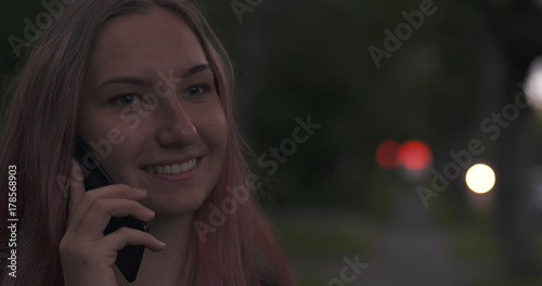 female teen talking on the phone on the street at night