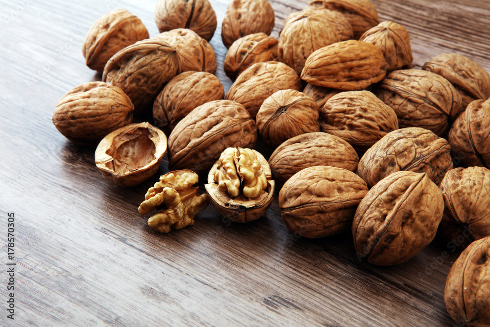 Walnut kernels and whole walnuts on brown wooden table. Walnut kernels and whole walnuts on brown wooden table.