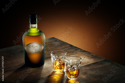 Photography view of glasses of  rum and a bottle aside on color background