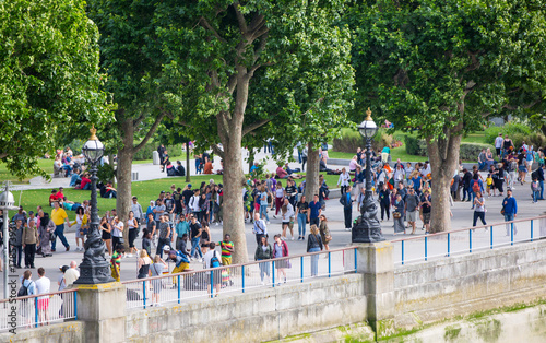 Lots of people, tourists and Londoners walking at the river Thames embankment next to the Westminster bridge. London, UK