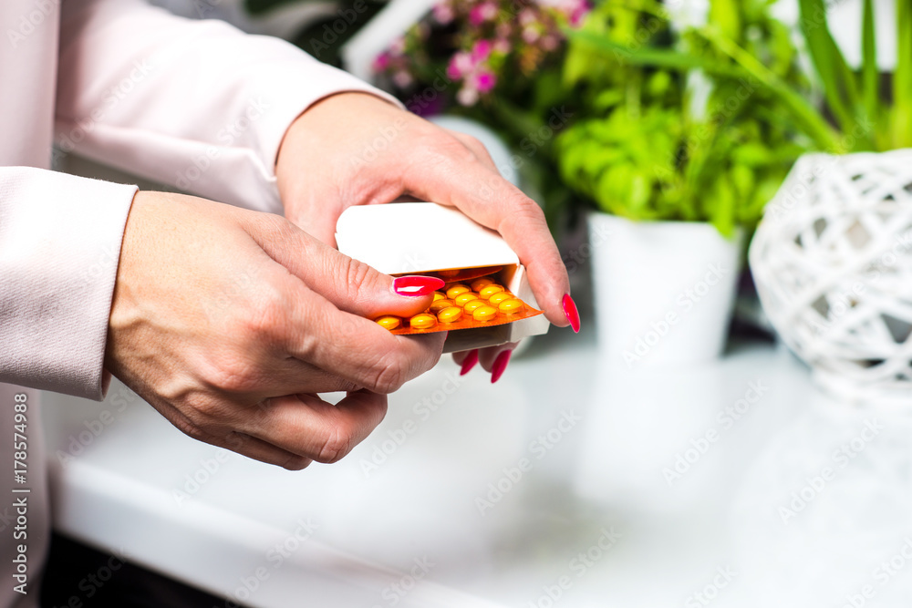 Pills, medicine, drugs on the table. Woman is holding her hands on the table and around the scattered white drugs. Reaches for drugs, is sick, taking large amounts of medication. Medicine concept. Pills, medicine, drugs on the table. Woman is holding her hands on the table and around the scattered white drugs. Reaches for drugs, is sick, taking large amounts of medication. Medicine concept.