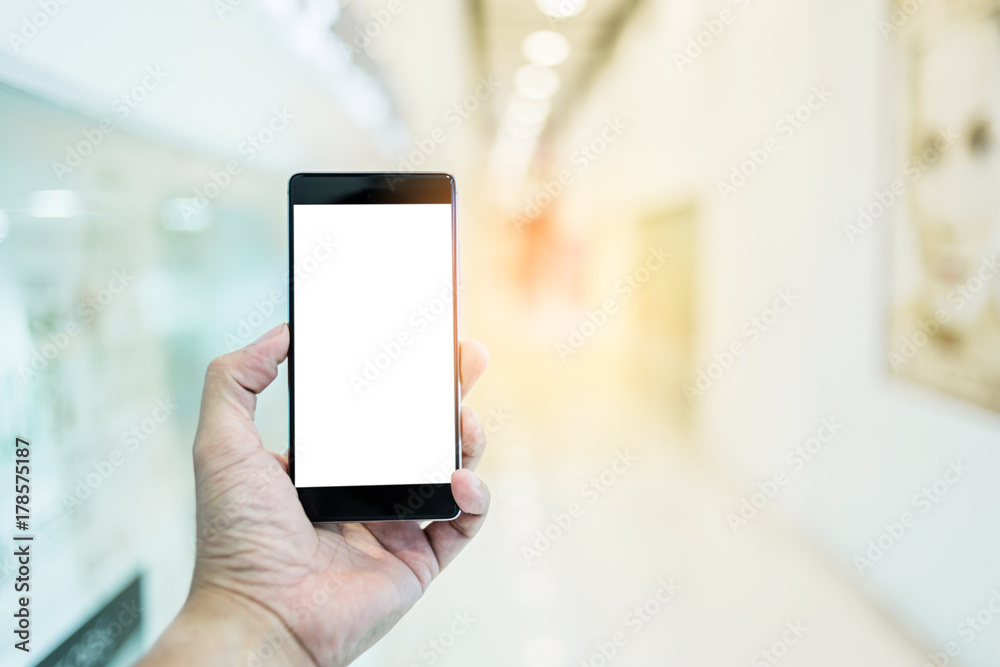 hand use smartphone with background of blur office corridor