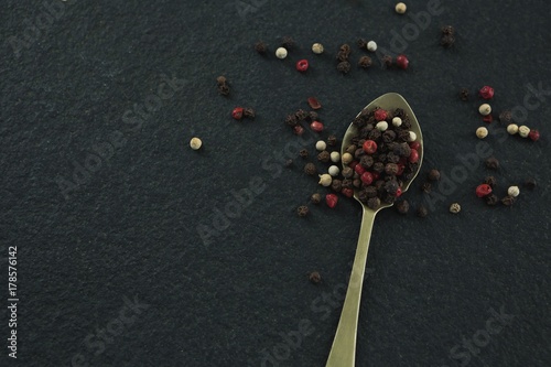 Black pepper and white pepper seeds in a spoon