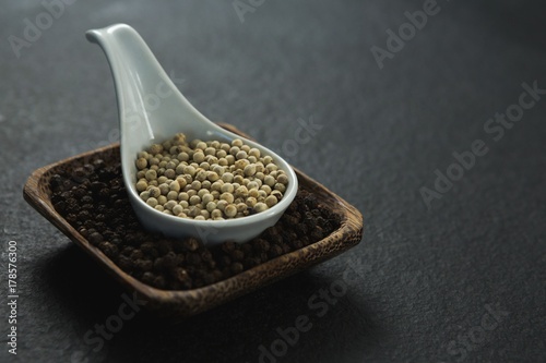 Black pepper and white pepper seeds in a bowl