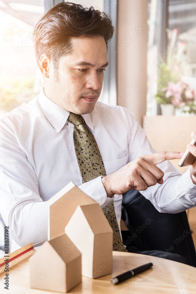 Businessman holding a little house over coffee shop background house business ideas concept Businessman holding a little house over coffee shop background house business ideas concept