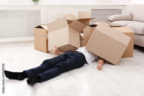 Bilde på lerret Man crushed underneath cardboard boxes