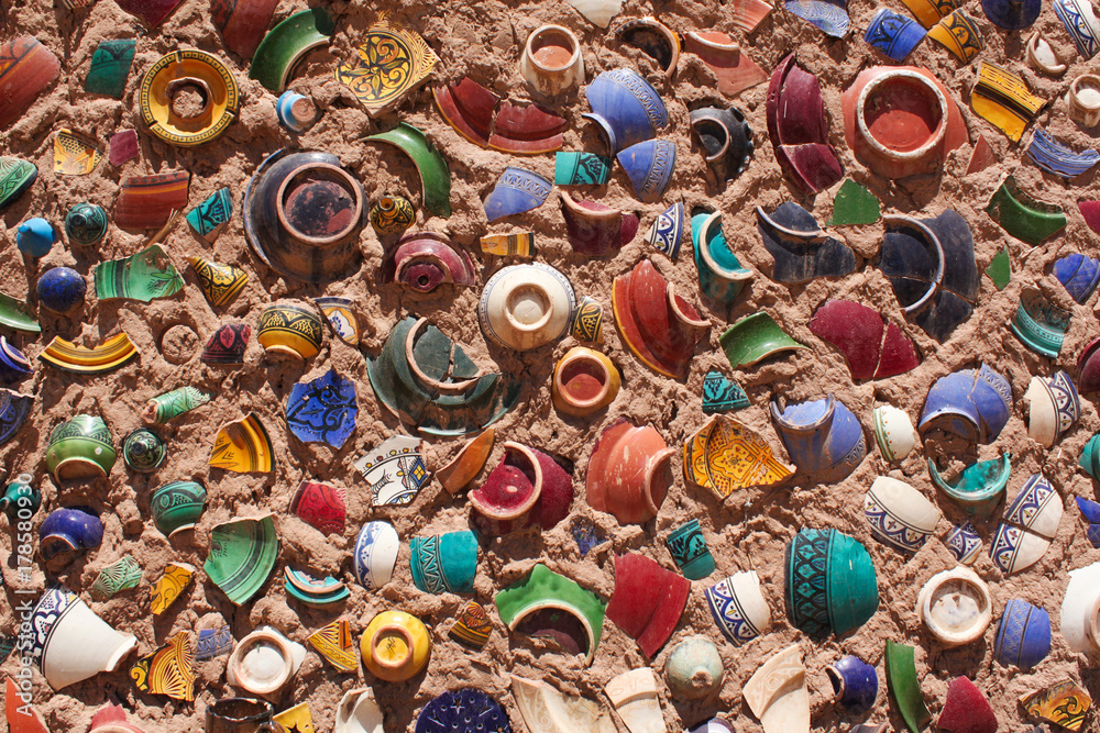 Colorful pieces of broken ceramic plates and bowls sticked on wall making decorative artistic wall.