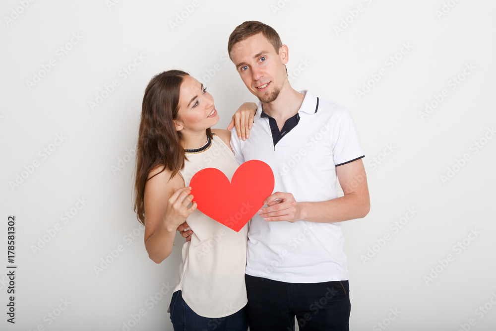Young happy couple in love holding red paper heart Young happy couple in love holding red paper heart
