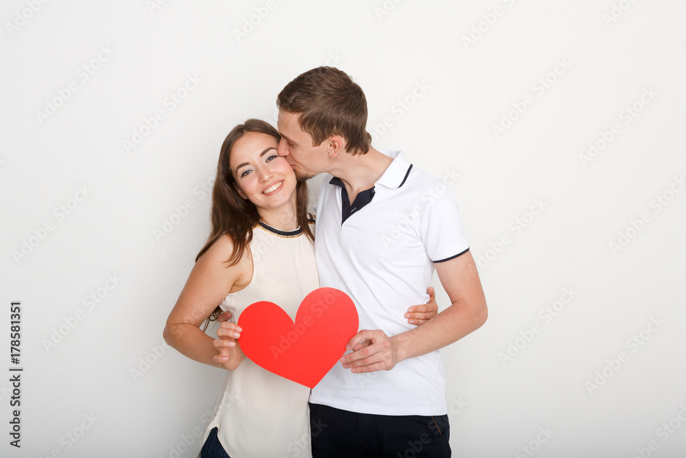 Young happy couple in love holding red paper heart