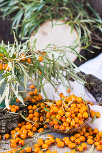 Berries of sea-buckthorn in a bowl on a wooden table