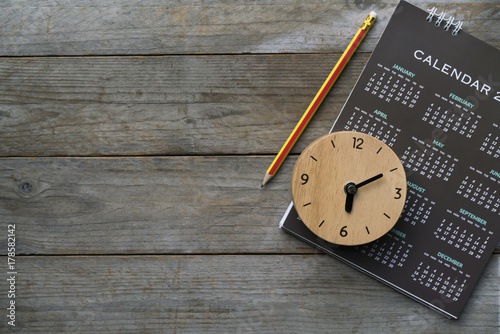 close up of clock, calendar and pencil on the table, planning for business meeting or travel planning concept photo