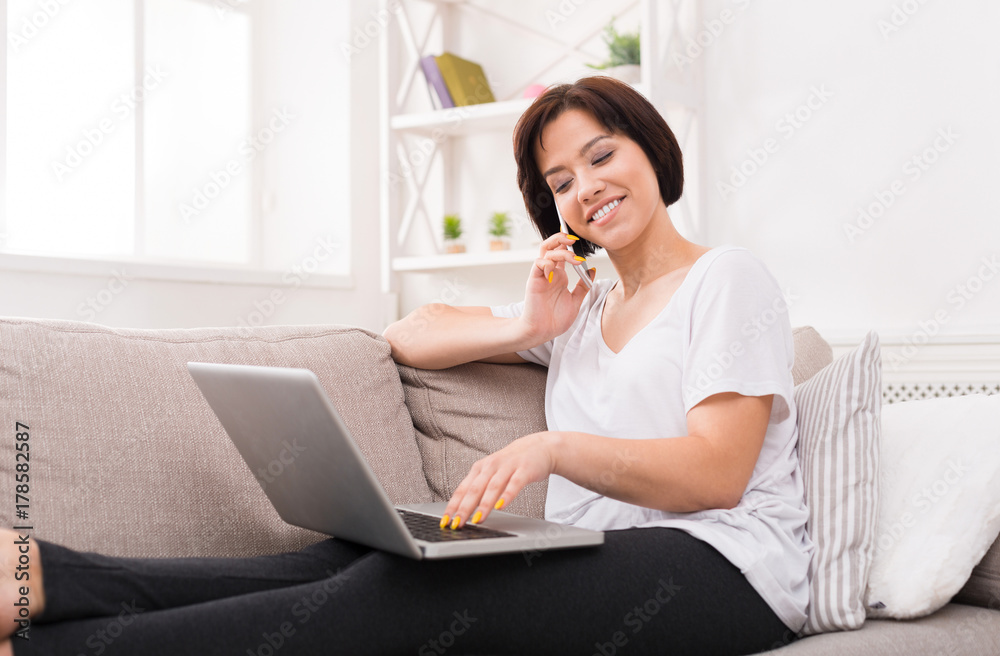 Young smiling beautiful woman with phone and laptop on the sofa Young smiling beautiful woman with phone and laptop on the sofa