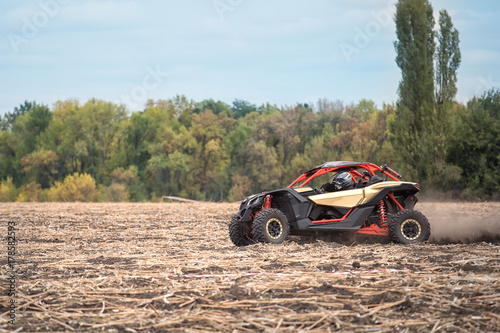 Quad bike is racing at high speed along an oblique field