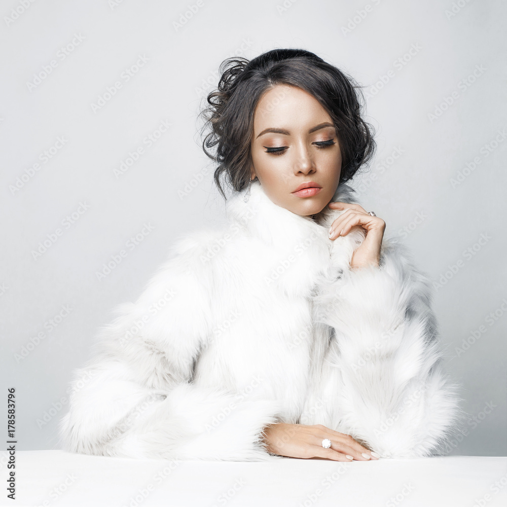 Beautiful woman with elegant hairstyle in white fur coat