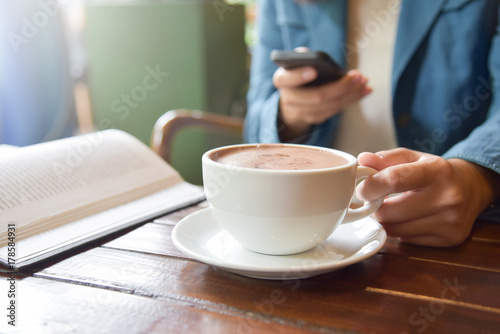 Woman Hands holding cup of coffee and using smart phone.