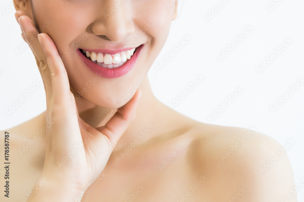 Closeup of young attractive woman with healthy teeth laughing with her hands on her face over white background Closeup of young attractive woman with healthy teeth laughing with her hands on her face over white background