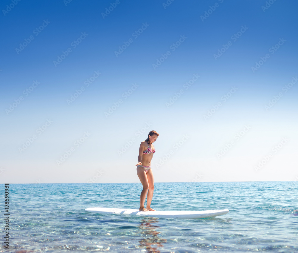 Attractive woman on a surf boarding in the sea, learning and newbie concept Attractive woman on a surf boarding in the sea, learning and newbie concept