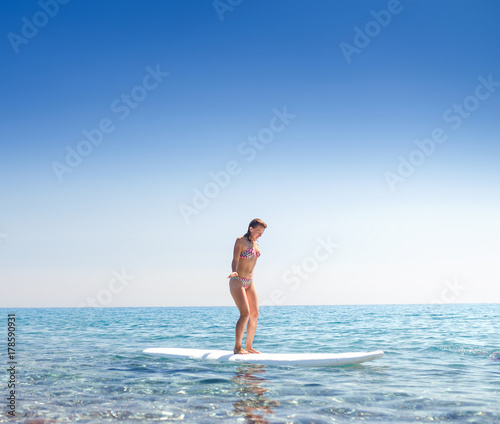 Attractive woman on a surf boarding in the sea, learning and newbie concept