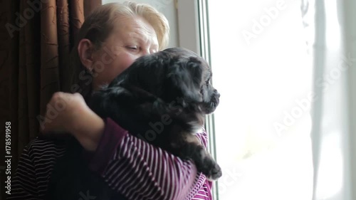 Elderly woman with her dog looking out the window. close-up photo