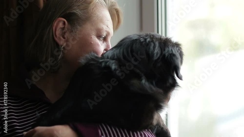 Mature mistress with a dog looking out the window photo