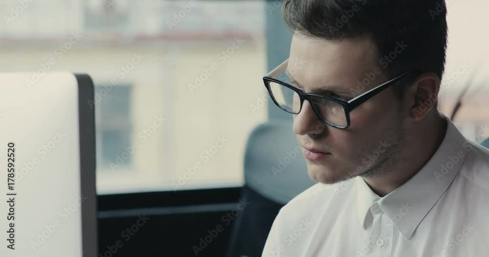 Serious man in glasses sitting at a desk uses a telephone in the office phone mobile technology modern smartphone male online talk tablet business communication Slow Motion Shot Serious man in glasses sitting at a desk uses a telephone in the office phone mobile technology modern smartphone male online talk tablet business communication Slow Motion Shot