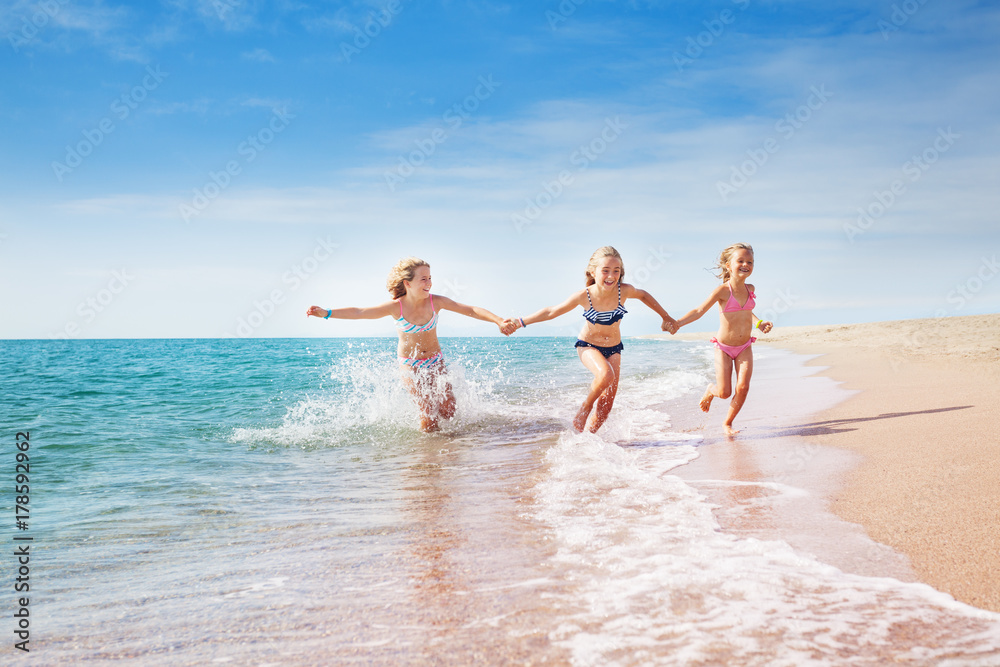 Girls running in sand and waves of sunny beach Girls running in sand and waves of sunny beach