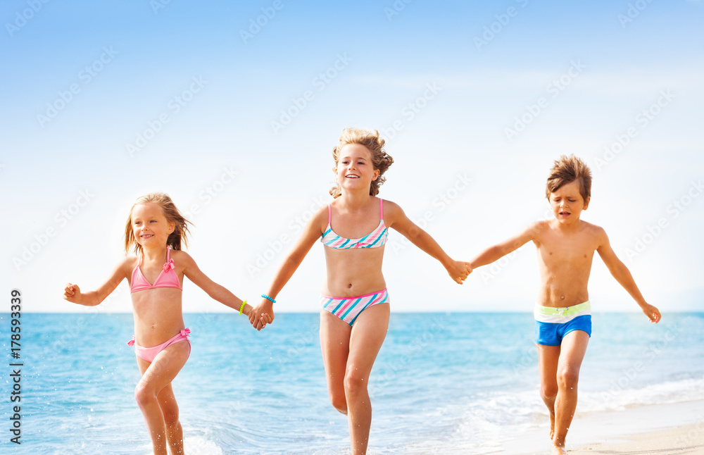 Happy friends running together along sandy beach Happy friends running together along sandy beach