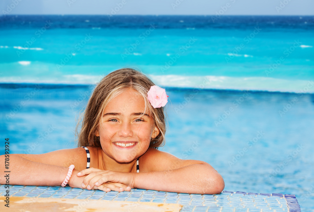 Smiling girl resting on the edge of swimming pool