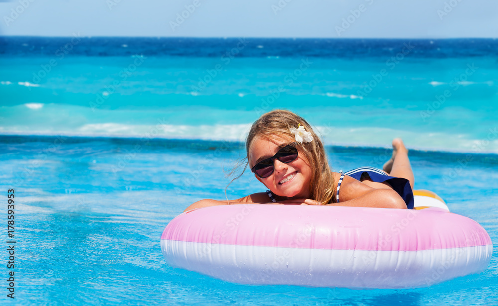 Smiling girl on inflatable mattress at seaside