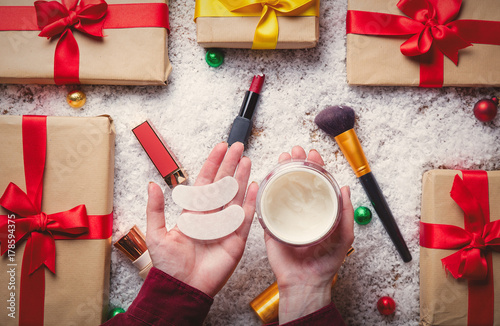 Woman hands holding makeup cosmetics with Christmas gifts