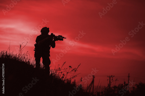 Silhouette of military soldier or officer with weapons at night. shot, holding gun