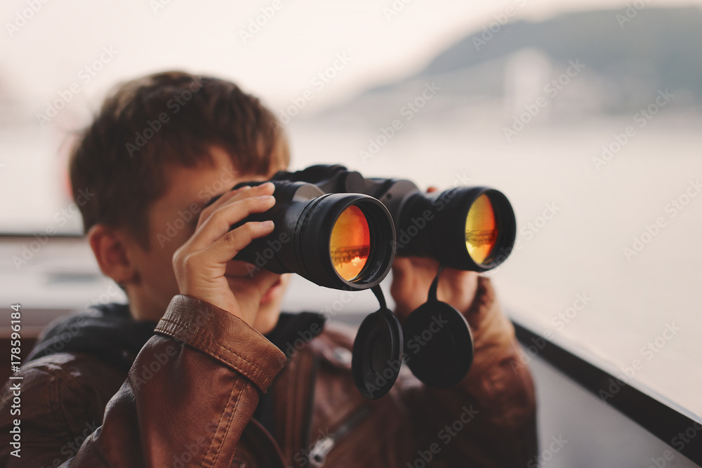 Little boy watching, looking, gazing, searching for by binoculars during trip