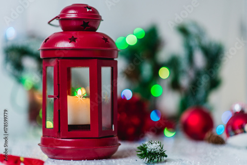 red Christmas lantern on white background with fir branches and lights garland