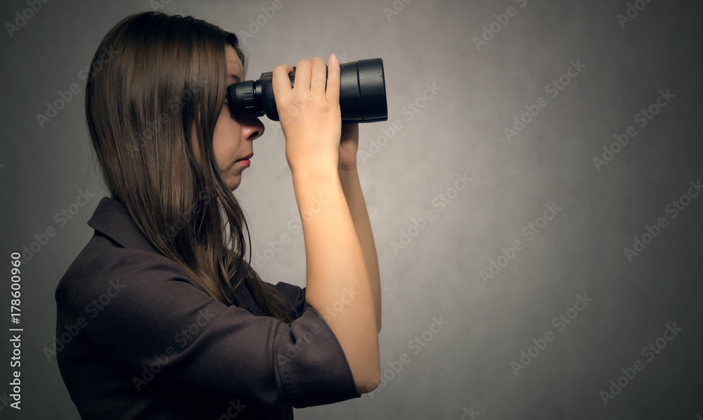 Young woman looking through binoculars from side view. Find and search. Young woman looking through binoculars from side view. Find and search.