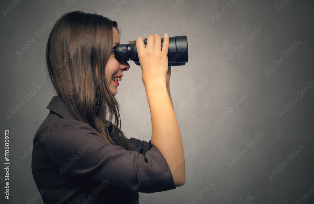 Young woman looking through binoculars from side view. Find and search. Young woman looking through binoculars from side view. Find and search.