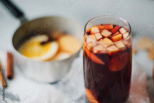 Fotografía Hot mulled wine in a glass with orange slices, anise and cinnamon sticks, star cookies on vintage wood table