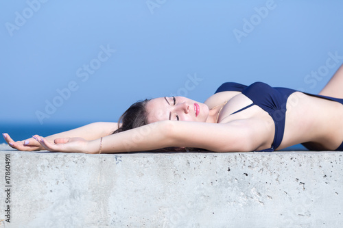 Waist-up portrait of girl in swimwear lying on back