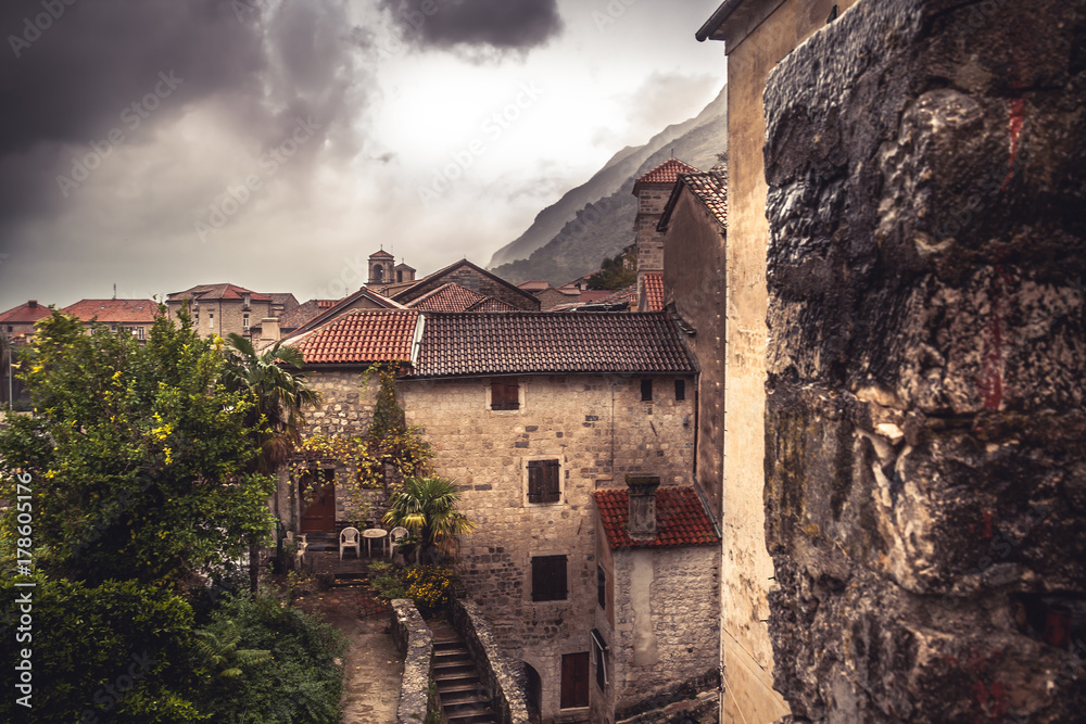 Medieval cityscape with tile roofs and ancient building facade in front of dramatic sky with antique architecture in old European town Kotor in Montenegro 