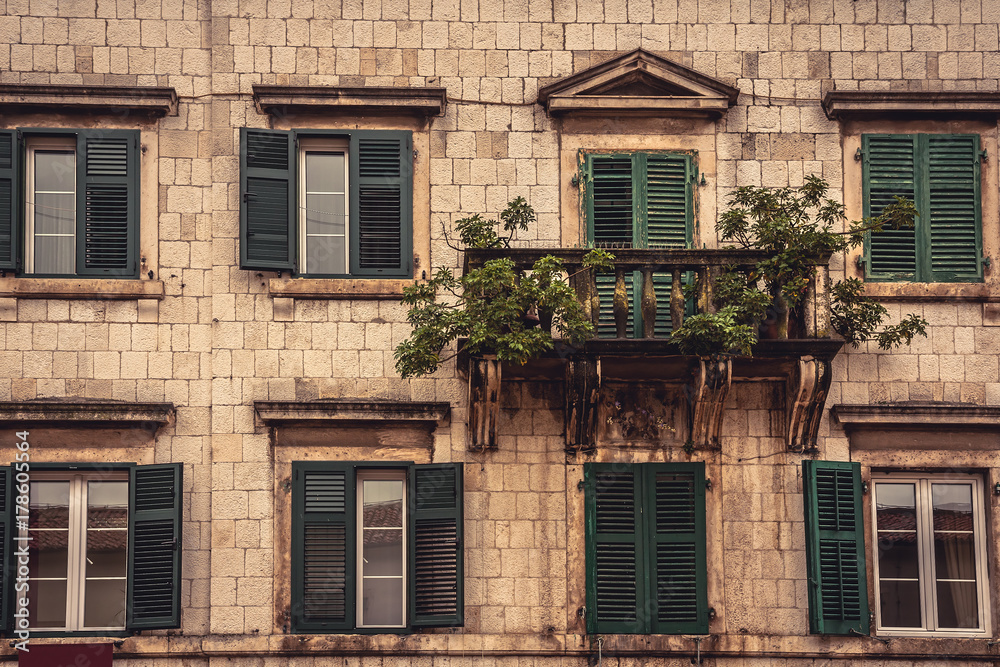 Old balcony with trees and flowers on old medieval building facade with windows in medieval architecture in ancient European city Kotor in Montenegro