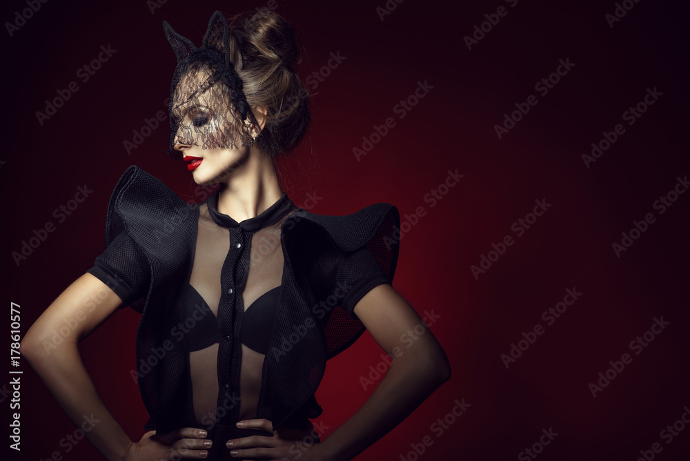 Gorgeous posh lady with updo hair and perfect make up wearing semi transparent lace bodysuit with frill sleeves and black lace cat ear veil mask hairband. Isolated on red background with closed eyes Gorgeous posh lady with updo hair and perfect make up wearing semi transparent lace bodysuit with frill sleeves and black lace cat ear veil mask hairband. Isolated on red background with closed eyes