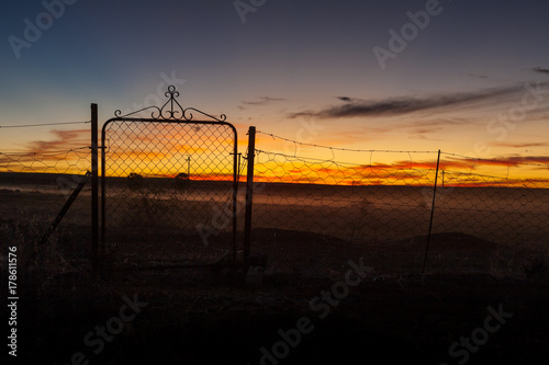 A silhouetted gate in the middle of nowhere at sunset