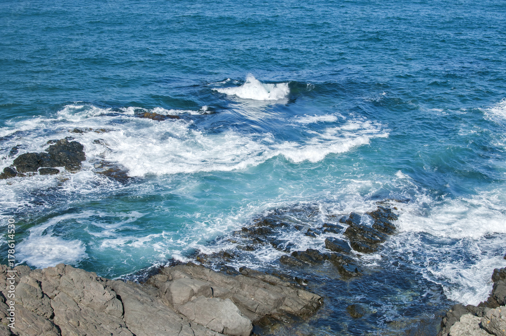 Landscape of rocky seashore with blue calm waters in sunny summer day as natural background