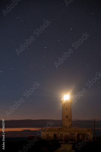 Lighthouse in the night against a starry sky