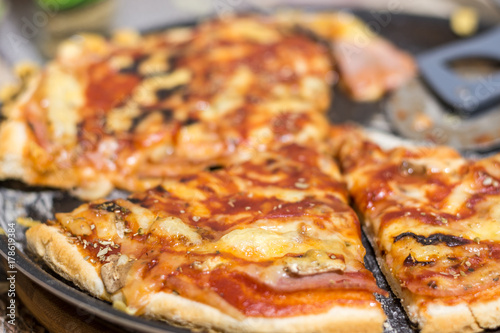 Świeża pieczona i pokrojona pizza z pieczarkami, szynką i serem