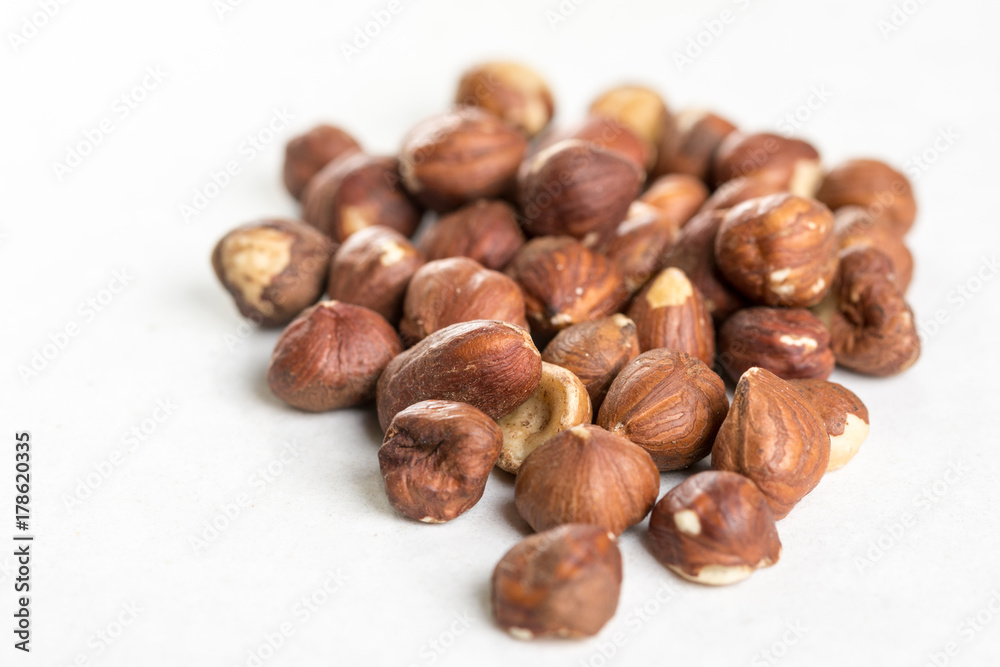 Pile of raw hazelnuts isolated above white marble stone Pile of raw hazelnuts isolated above white marble stone