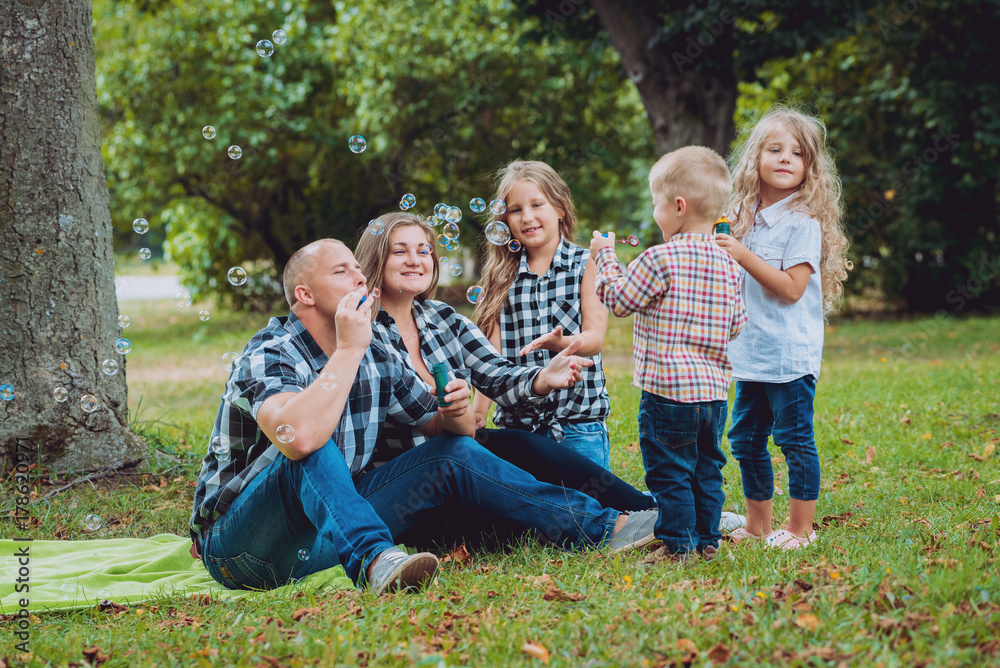 Fototapeta premium Young family with cheerful children in the park